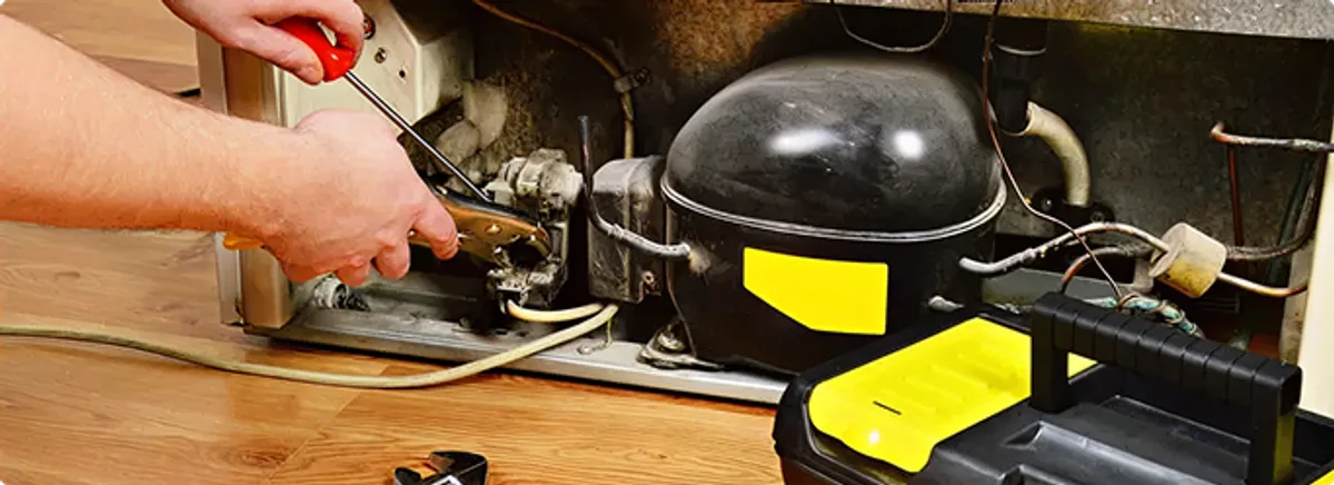 Refrigerator repair technician fixing the compressor and wiring in Dunedin, FL