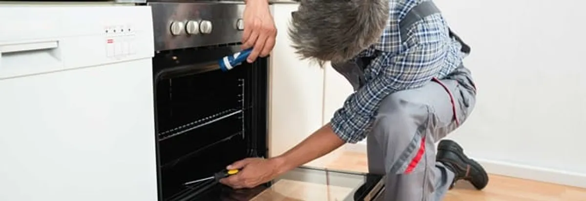 Oven repair technician inspecting and servicing an electric oven in Clearwater, FL