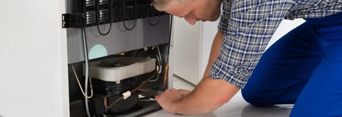 Refrigerator repair technician servicing the compressor and condenser area in Clearwater, FL